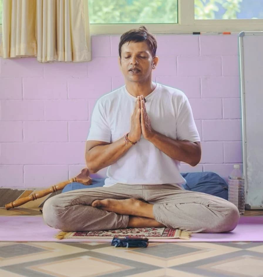 Somashekar, head teacher at Anantadrishti Yoga, seated in meditation with palms together in namaste in Rishikesh